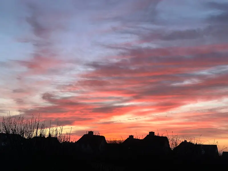 Glühender Himmel über den Reetdächern
