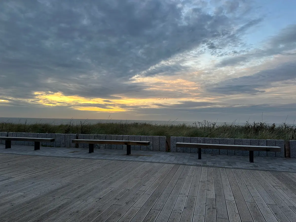 Promenade in Wenningstedt mit Bänken, Dünengras und Sonnenuntergang über der Nordsee